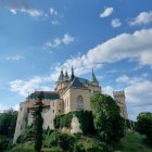 Ancient castle on lush green hill under blue sky.