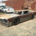 Vintage cars in neglected street with wooden shacks and hazy atmosphere