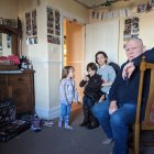 Family of five celebrates Christmas at home with tree, lights, and presents