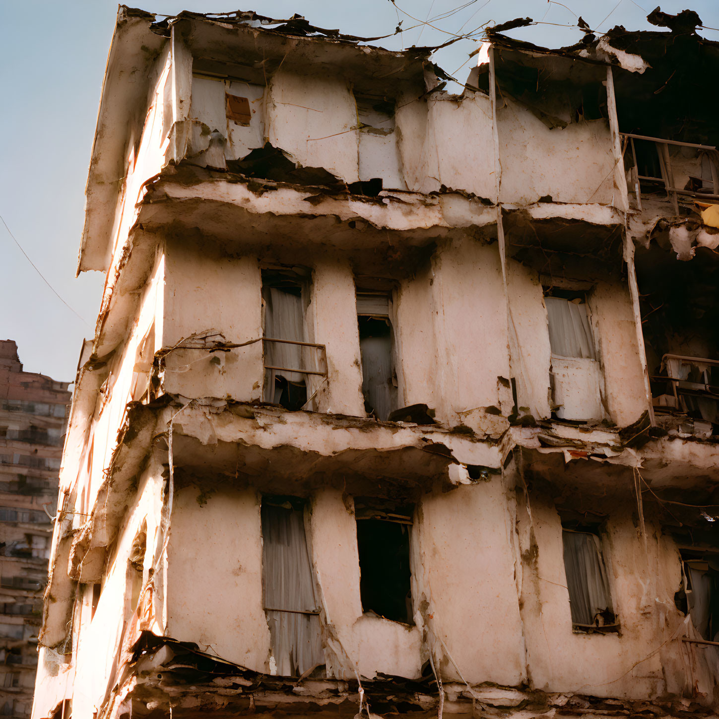 Decaying multi-story building with damaged exterior walls and window frames.