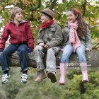 Three children on tree branch in colorful clothes in magical forest scene