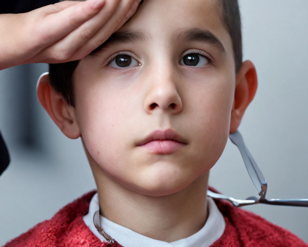 Young Boy Getting Haircut Holding Glasses with Hand on Forehead