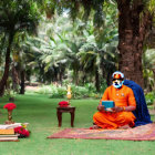 Man in Orange and Blue Robes Reading Book Surrounded by Birds in Nature Scene