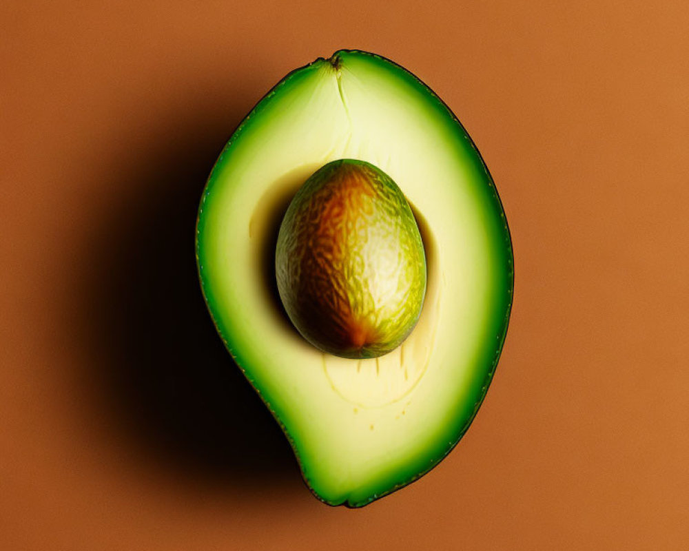 Ripe Avocado Halved with Visible Seed on Brown Background