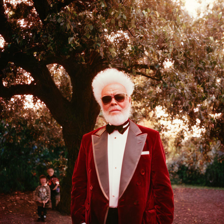 Elderly person in red velvet jacket under tree with child in background