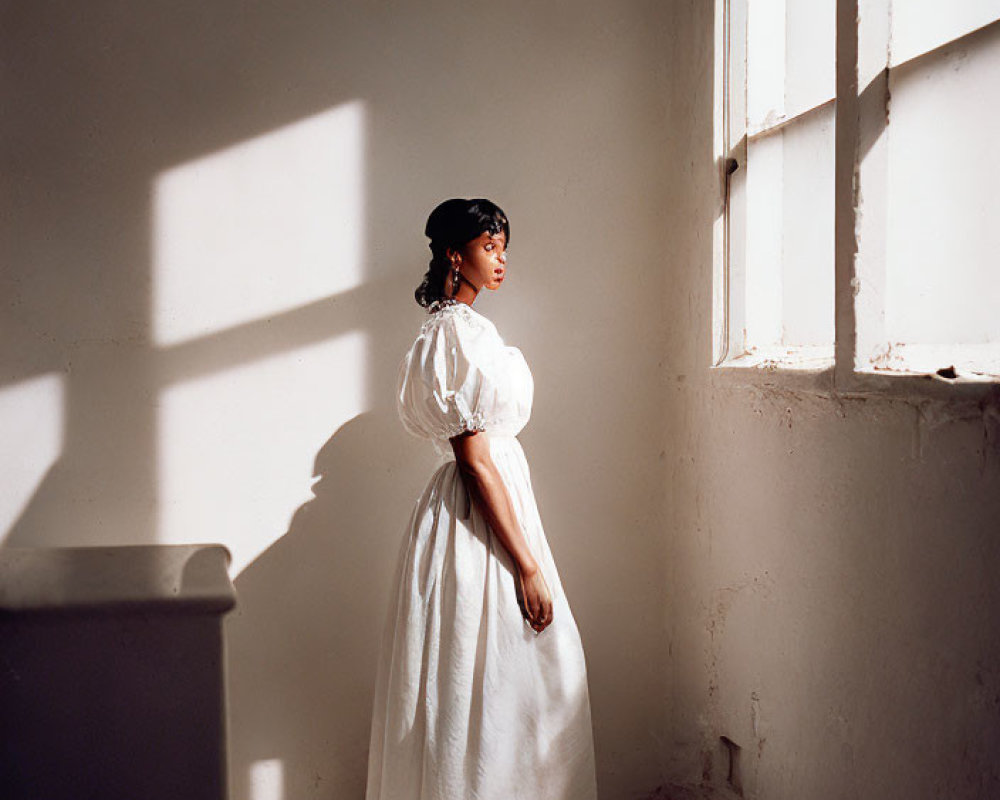 Vintage woman in white dress and hat by window with strong shadows