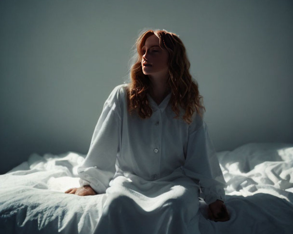 Woman in White Dress Sitting on Bed with Rumpled Sheets