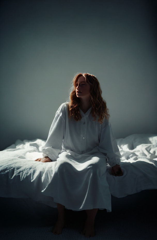 Woman in White Dress Sitting on Bed with Rumpled Sheets