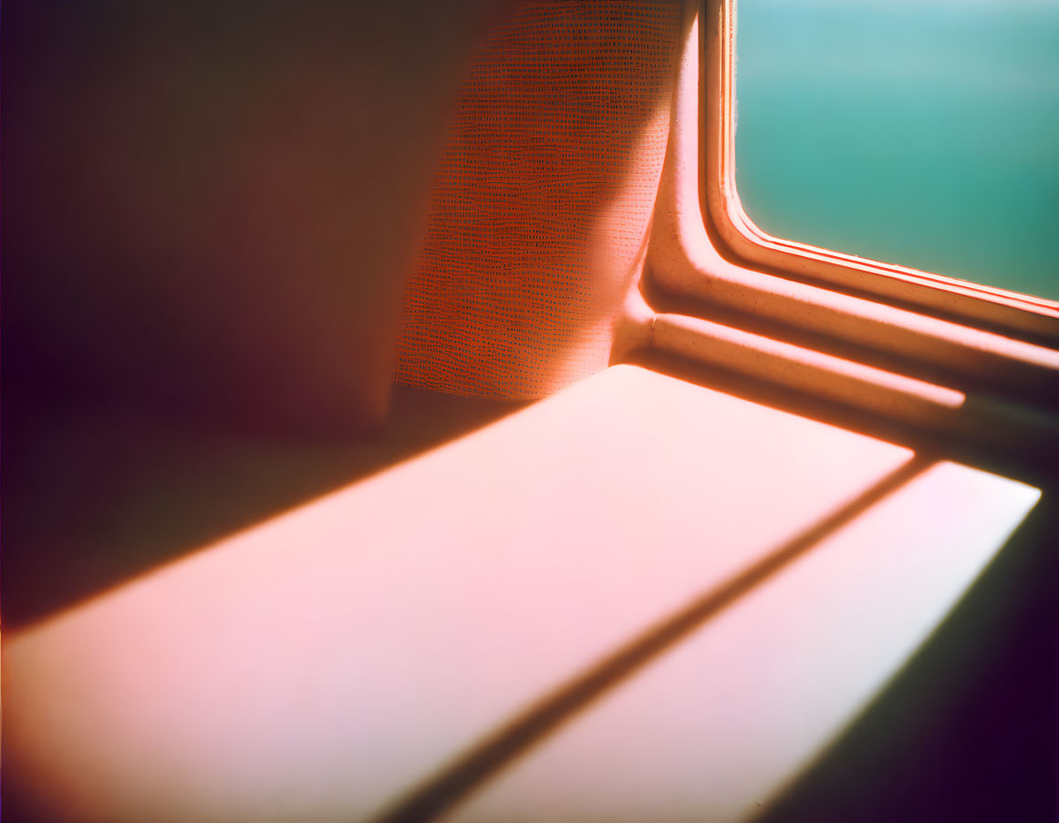 Sunlight illuminating train interior with orange seat and floor