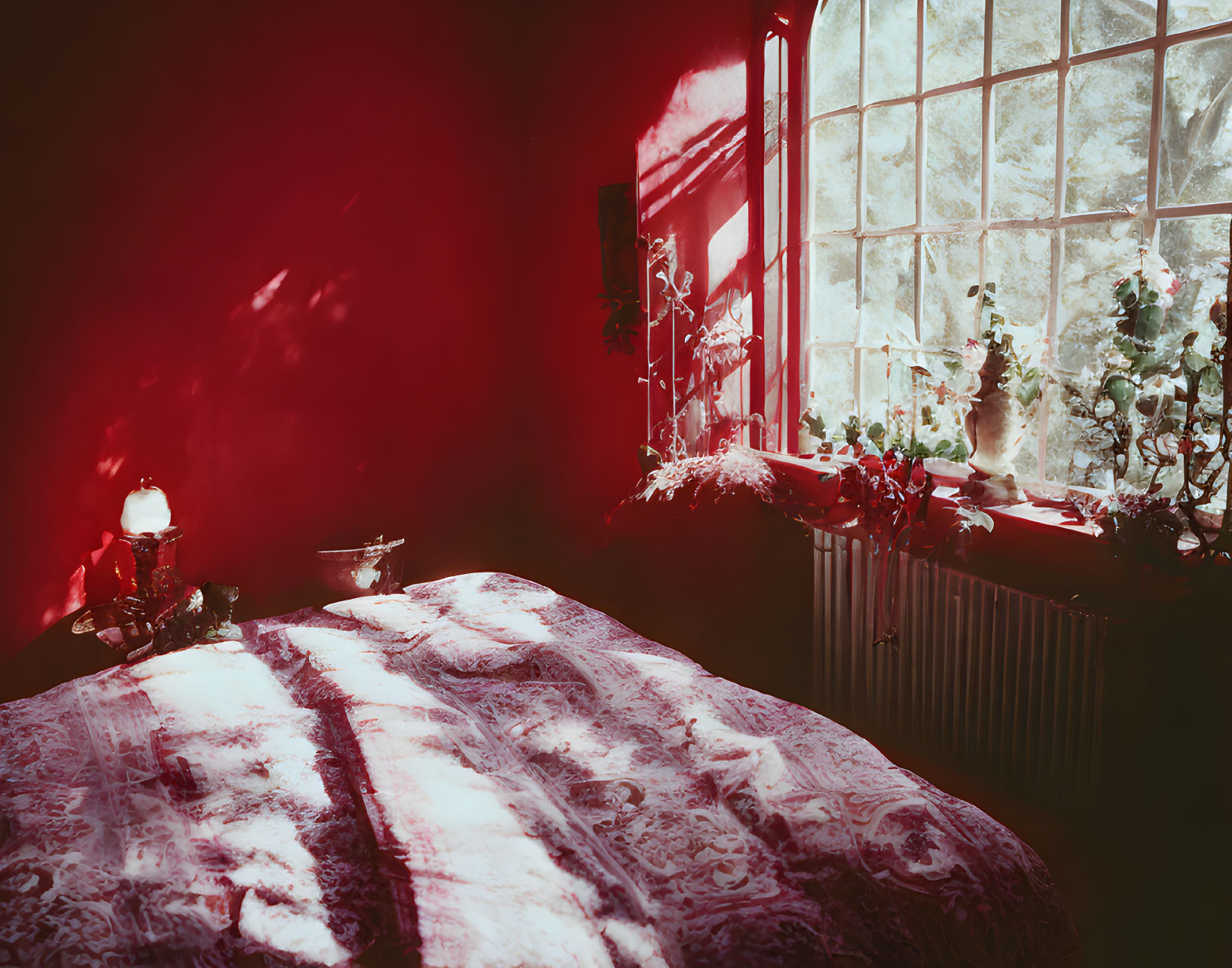 Vintage-style bedroom with red lighting, ornate bedspread, candle, ivy window.