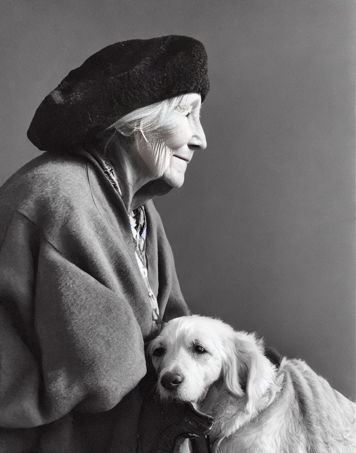 Elderly woman in beret embracing light-colored dog profile.