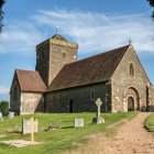 Quaint church with bell tower in lush greenery and wooden fence path