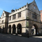 Vintage attire street scene outside elegant stone building under clear blue sky