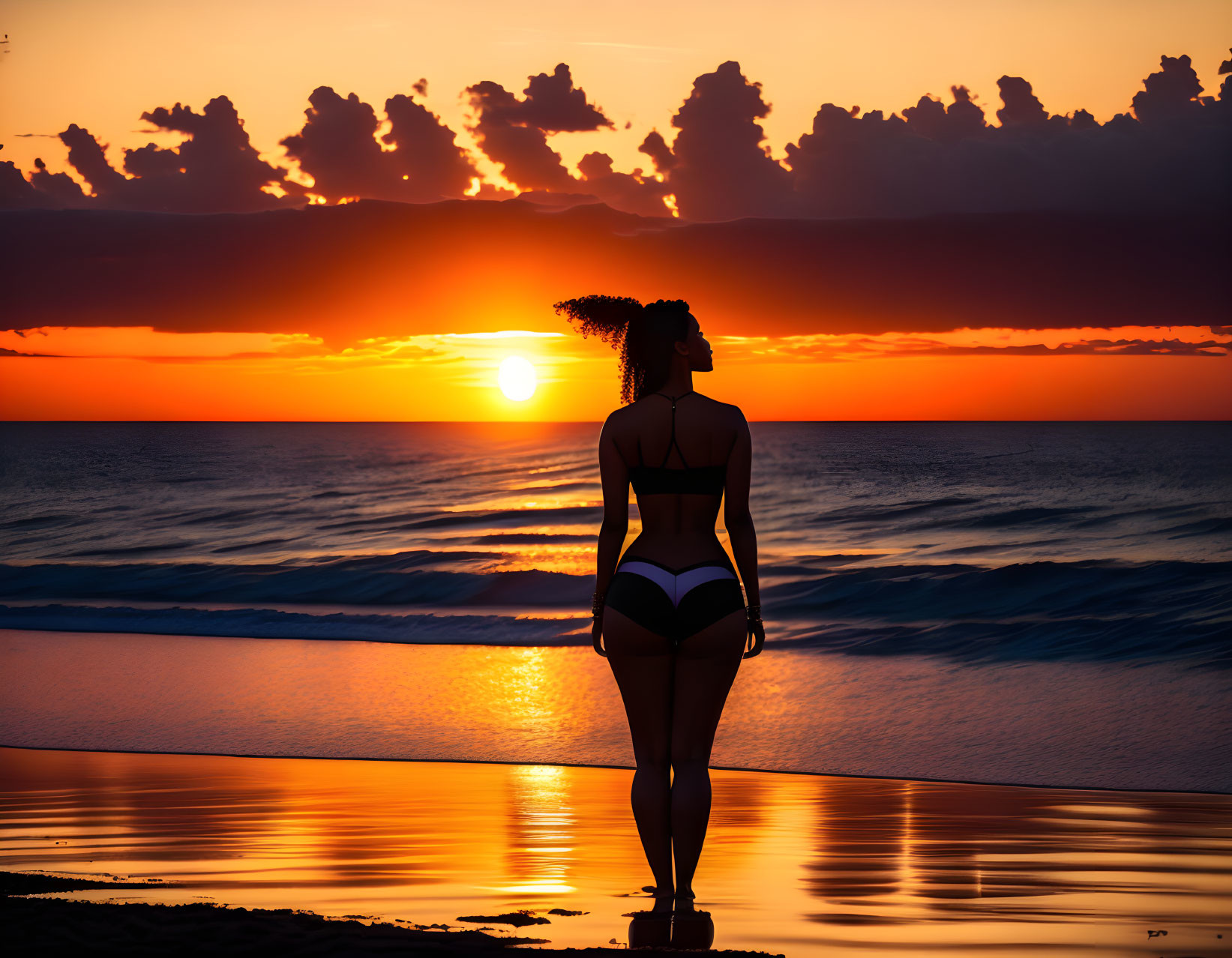 Silhouetted woman on beach at sunset gazing at sea