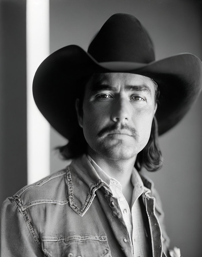 Monochrome portrait of man in cowboy hat and denim shirt