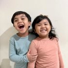 Children with robotic arm smiling on light background