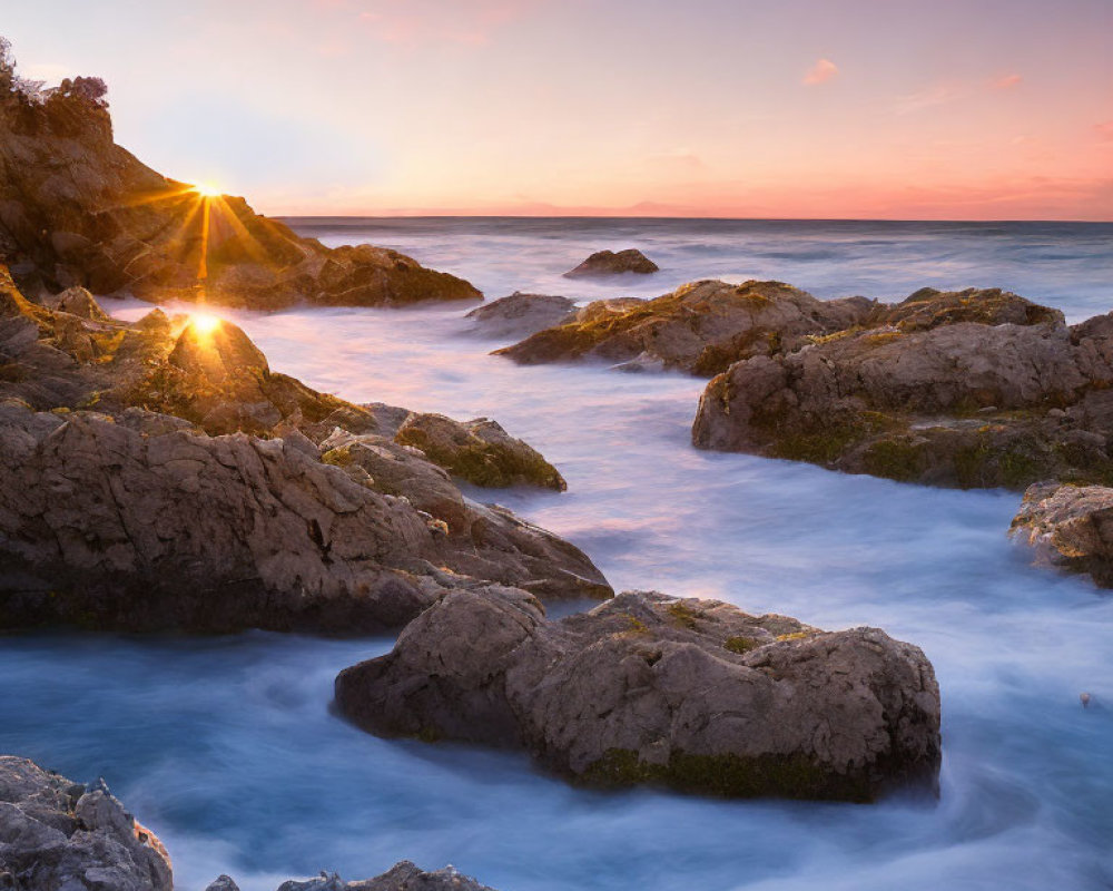 Tranquil sunset over rocky beach with golden sun rays