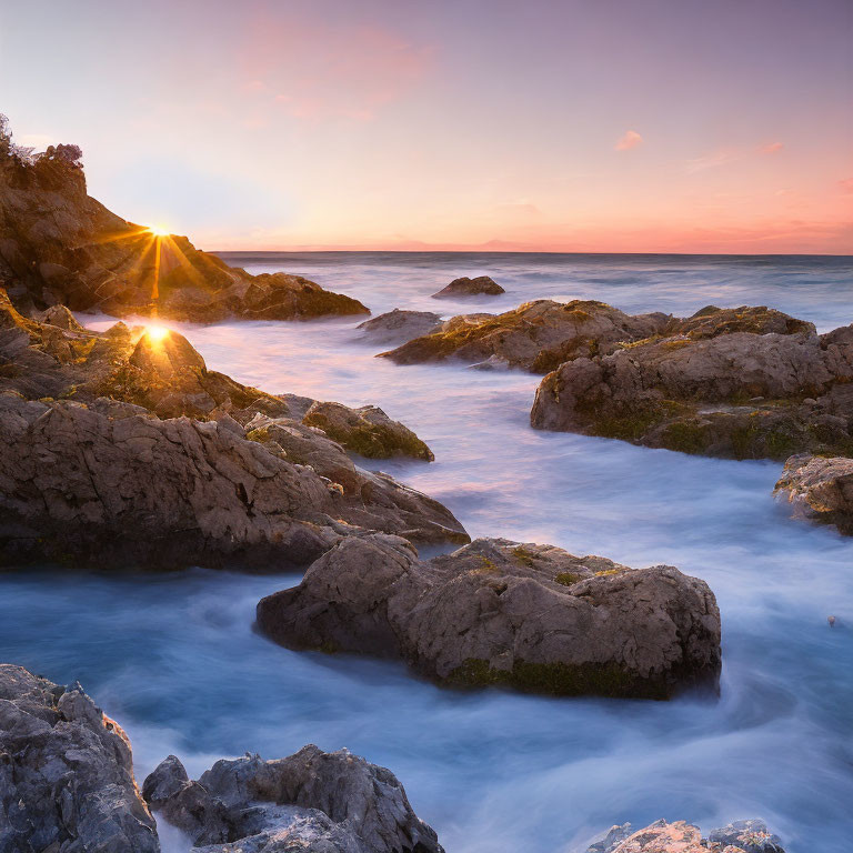 Tranquil sunset over rocky beach with golden sun rays