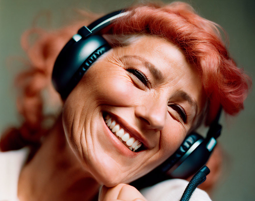 Pink-haired woman laughing with headphones in blurred background