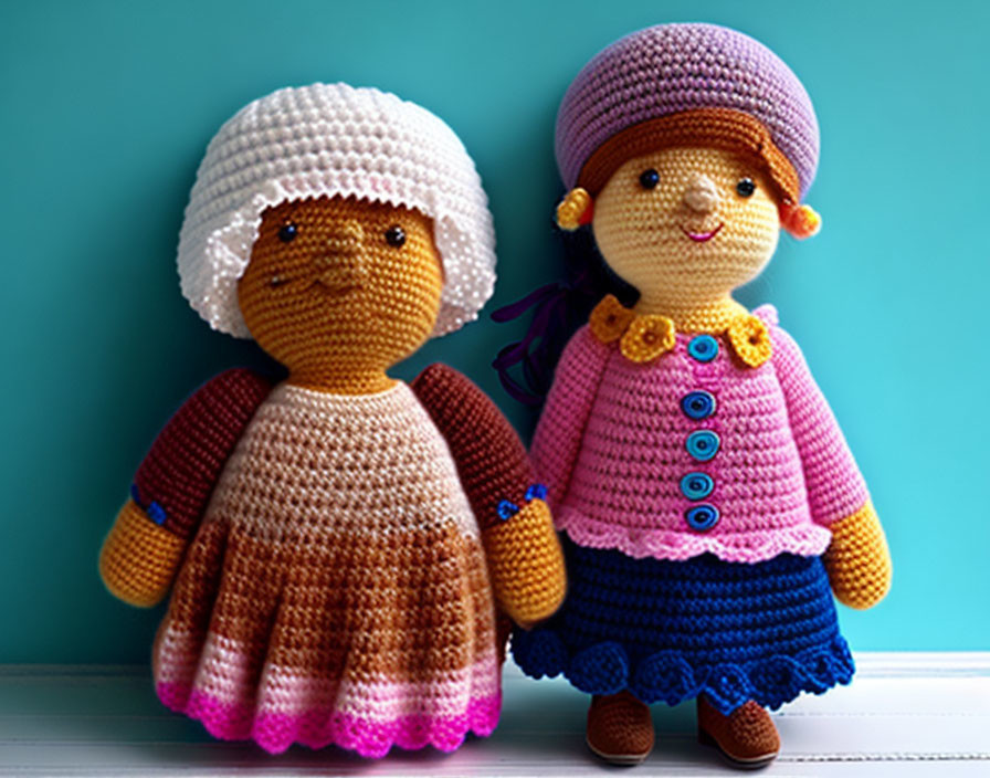 Colorful crocheted dolls with bonnets and dresses on teal background