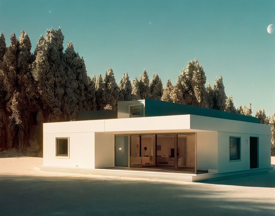 Minimalist white house with large glass windows in snowy twilight scene.