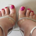 Feet with pink toenail polish in clear rhinestone sandals