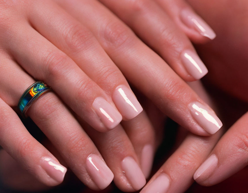 Manicured hands with pink nails and colorful ring