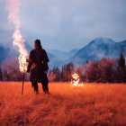 Mystical person with flaming staff in fantasy landscape