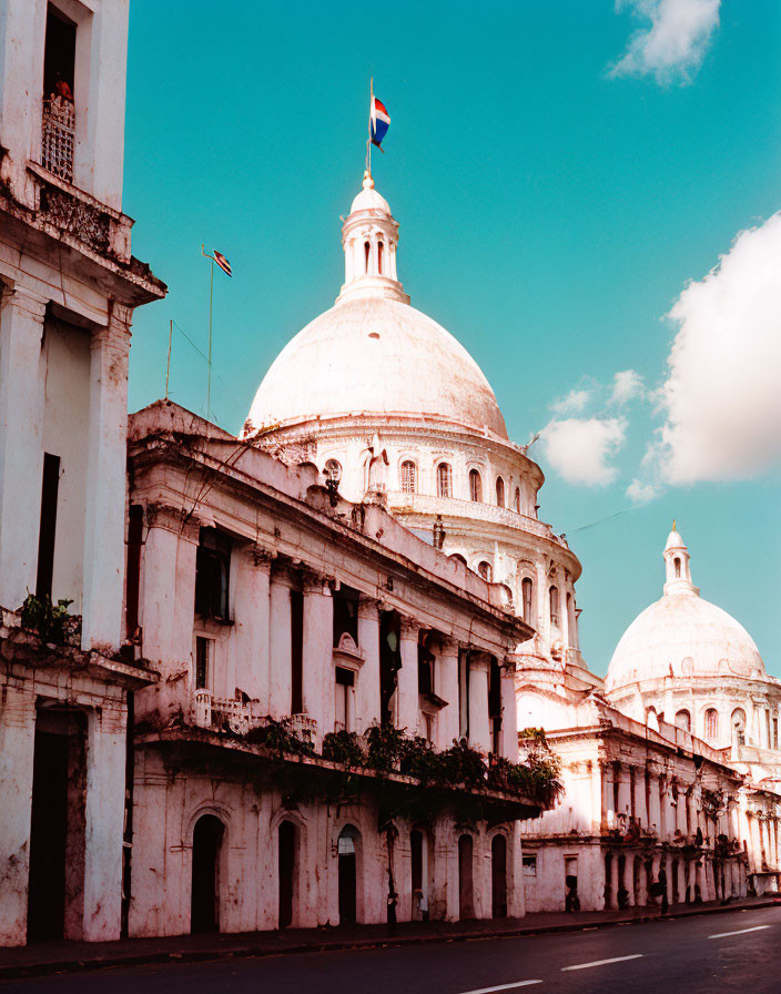 Historic white building with large dome and flag against blue sky