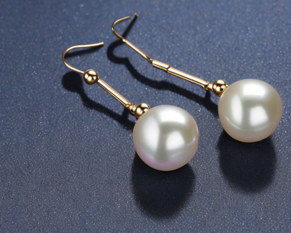 Pearl Drop Earrings with Gold Hooks on Dark Blue Surface