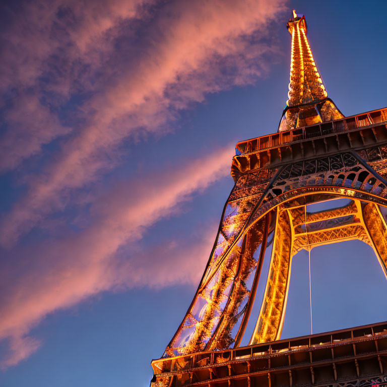 Iconic Eiffel Tower at twilight with vibrant sky and wispy clouds.