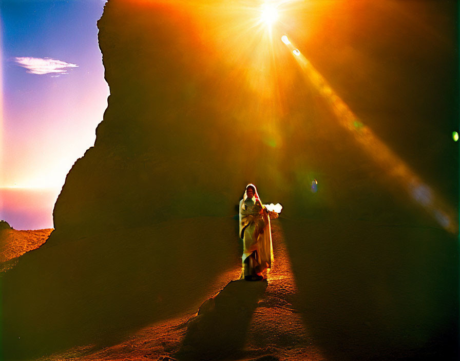 Person in robe beside rock formation under bright sun with silhouette effect