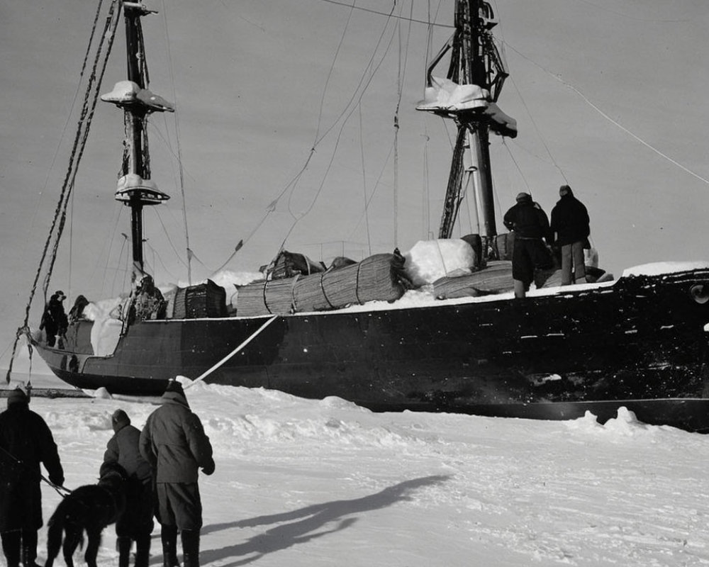 Monochrome photo of people, dog, and ship in ice with cargo and masts.