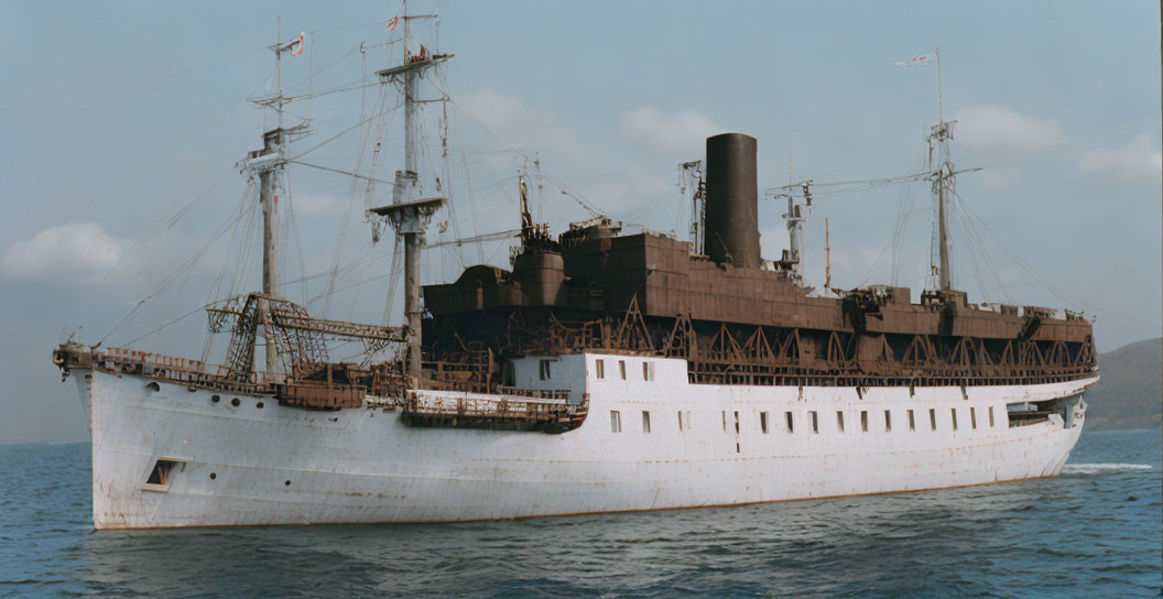 Vintage cargo ship with single smokestack and cranes sailing on calm seas