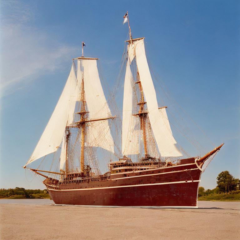 Traditional sailing ship with two masts and red hull in calm waters