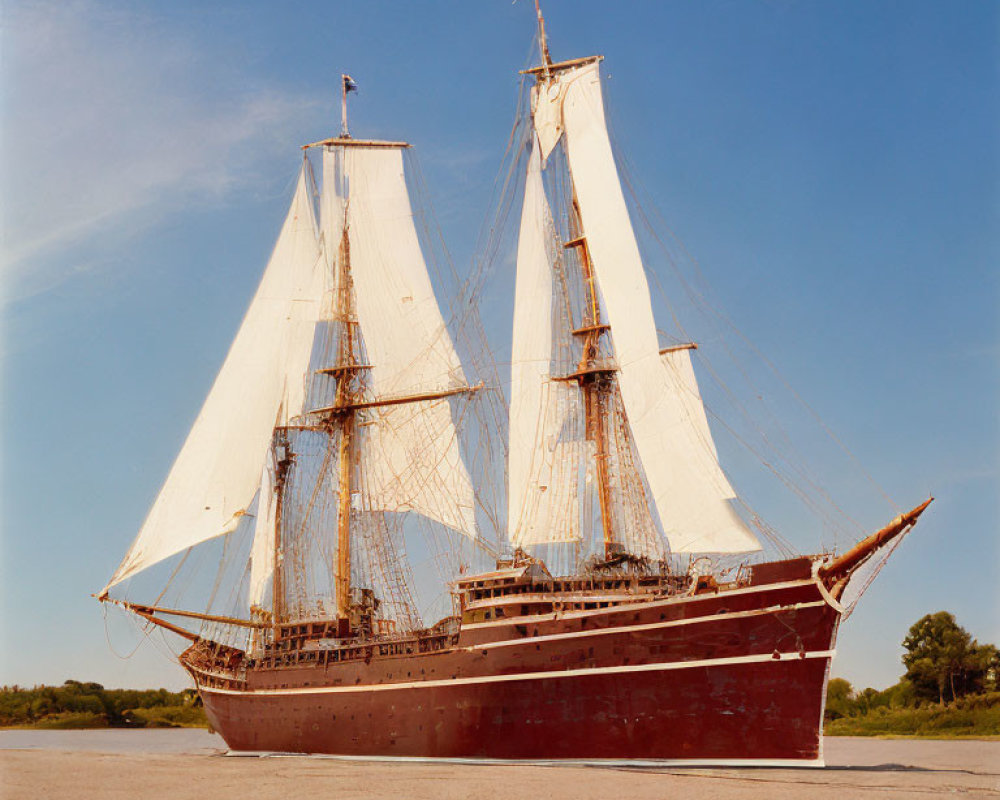 Traditional sailing ship with two masts and red hull in calm waters