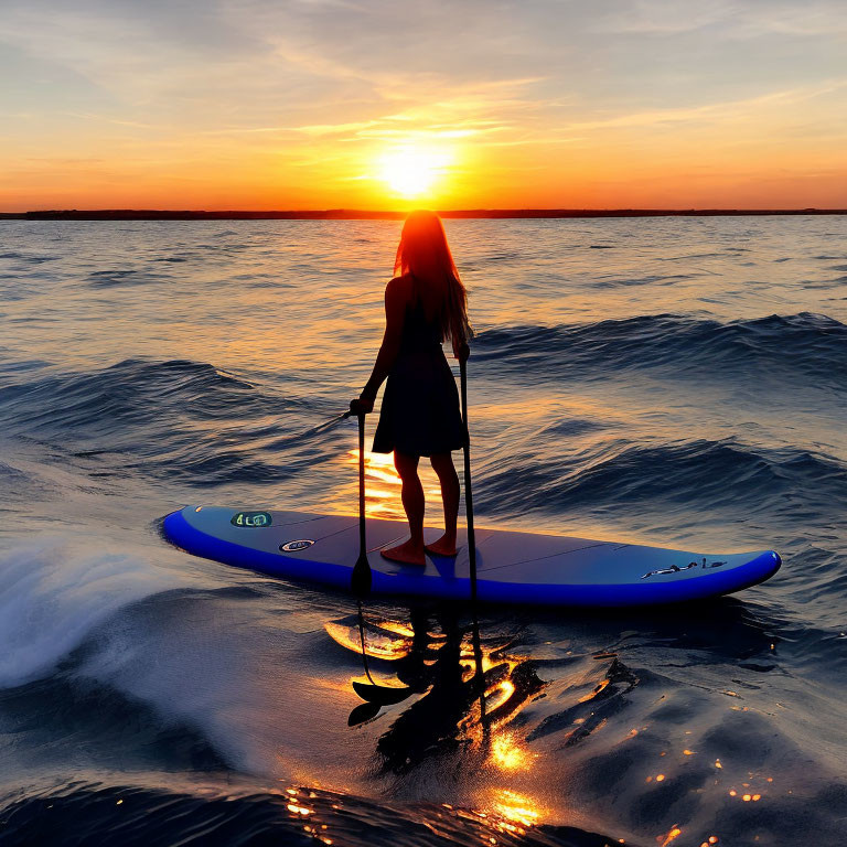 Silhouette of person paddleboarding at sunset on serene sea