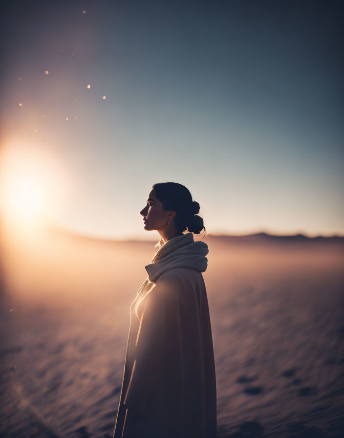 Woman in coat silhouette in desert sunset glow