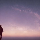 Silhouette of person on hill under starry Milky Way at twilight