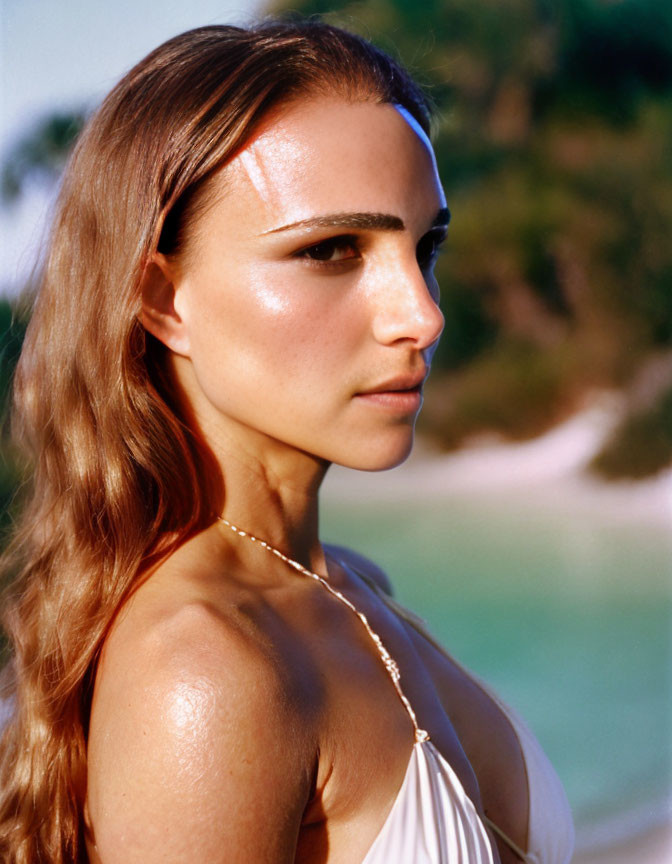 Woman with sun-kissed skin in white top and necklace gazes serenely.