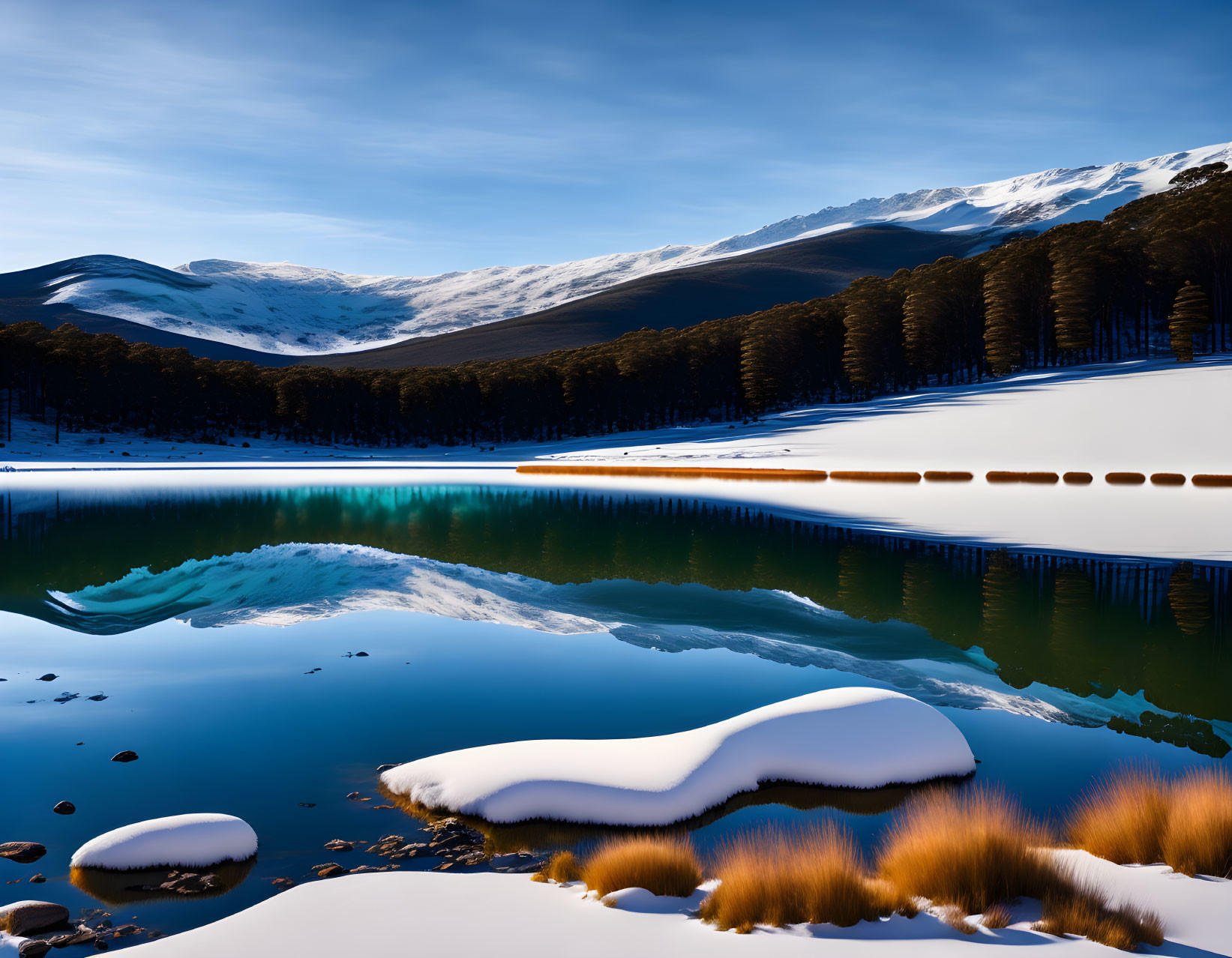 Snowy mountains reflected in blue lake amidst winter landscape