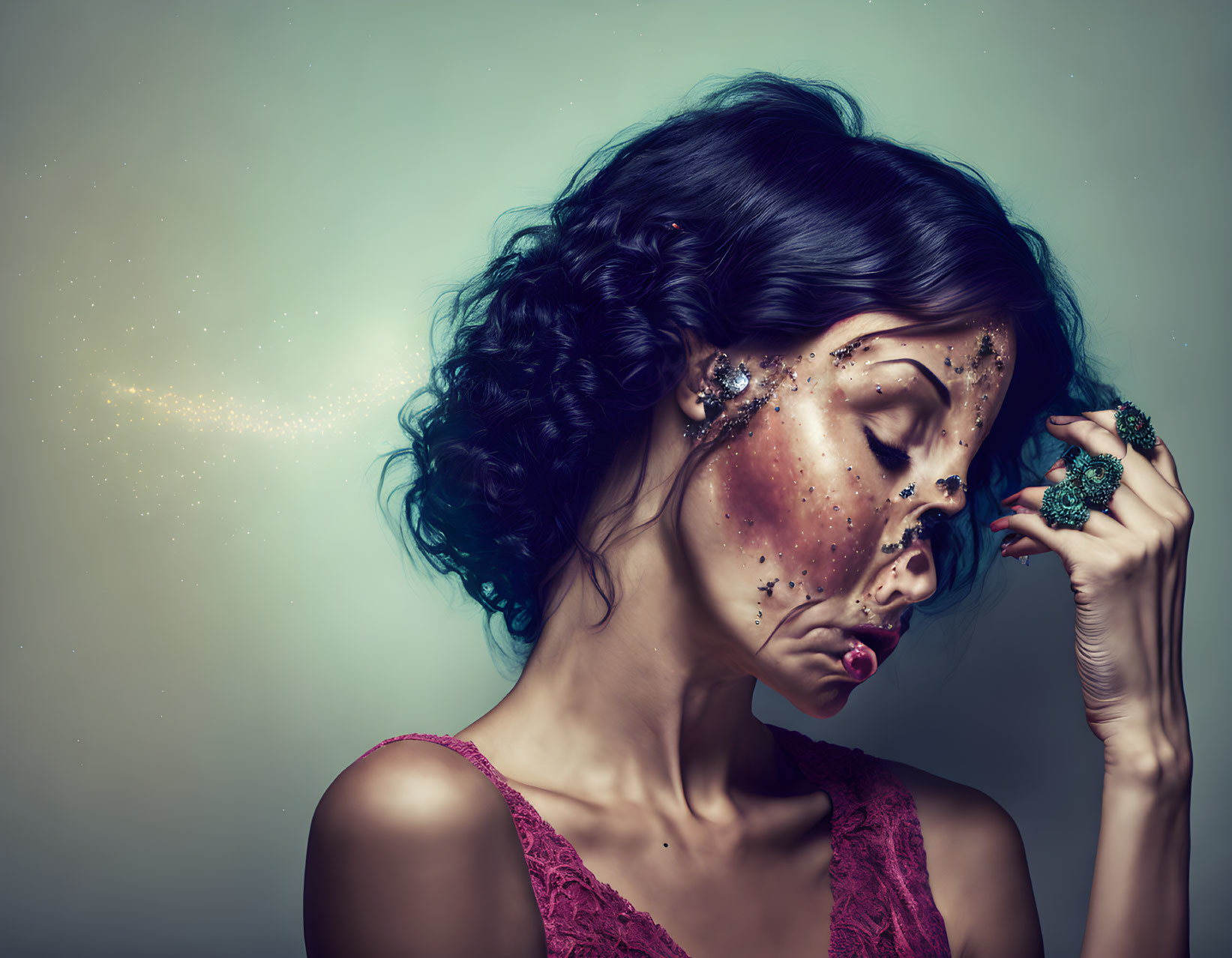 Woman with cosmic makeup, glittering stars, curly hair, red dress & large ring