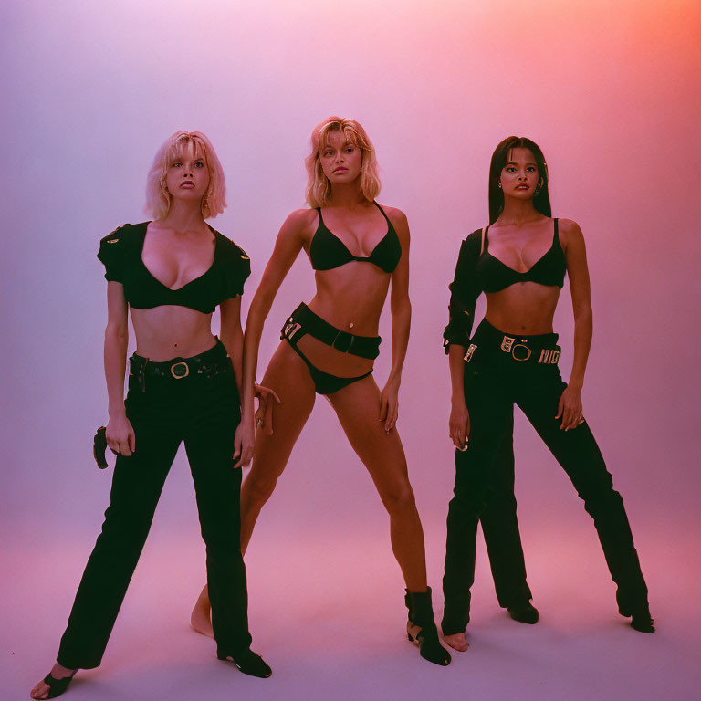 Three Women in Black Outfits Against Pink and Purple Background