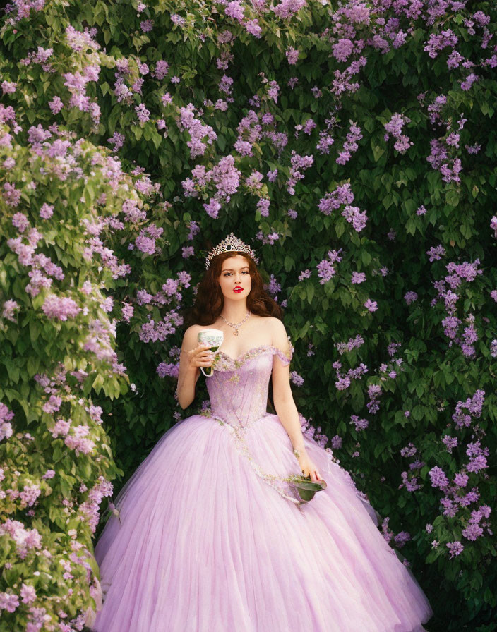 Woman in Purple Gown Poses with Cup and Saucer in Front of Lilac Flowers