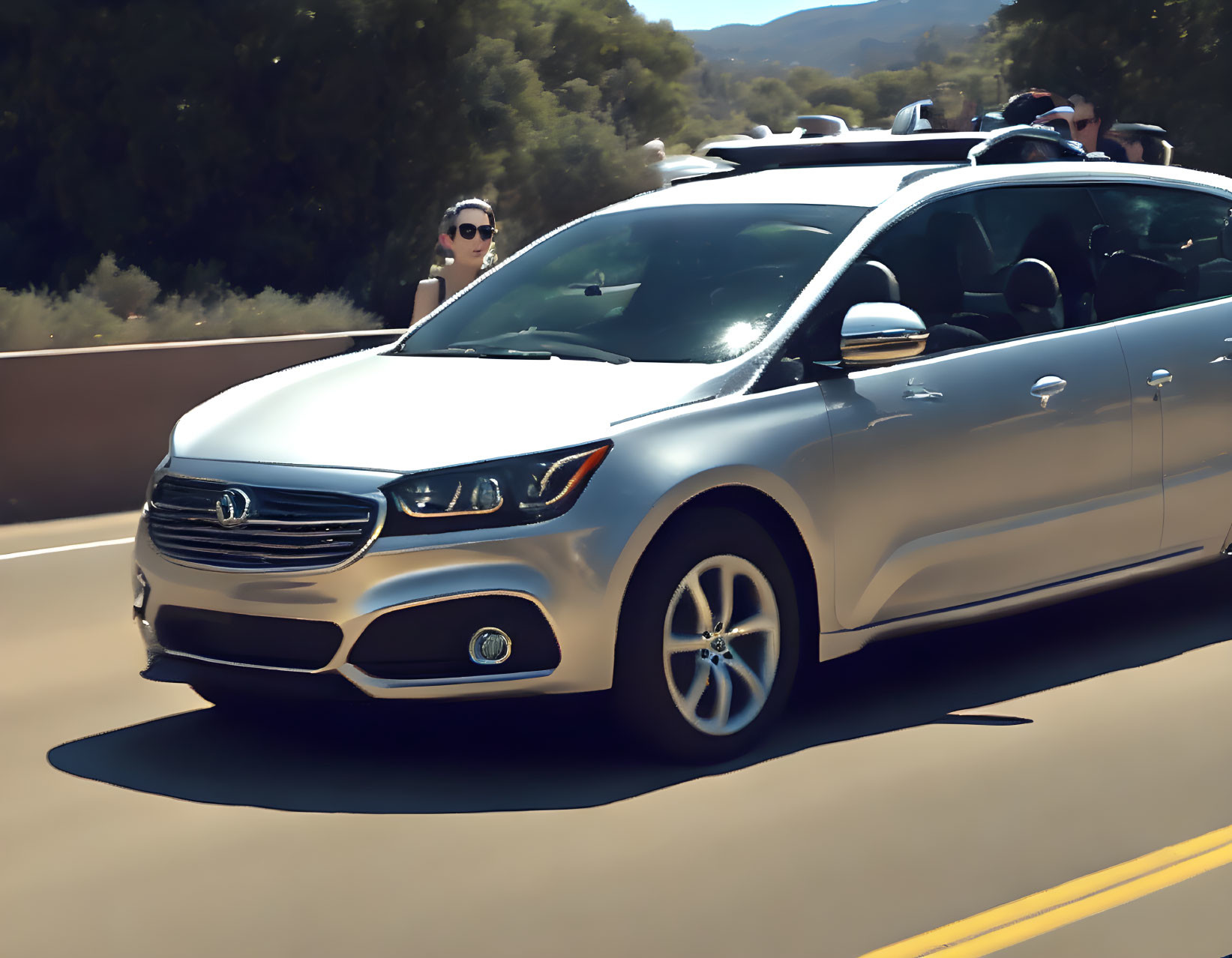 Silver sedan with sunroof open, passenger enjoying breeze on sunny day, driving on tree-lined road.