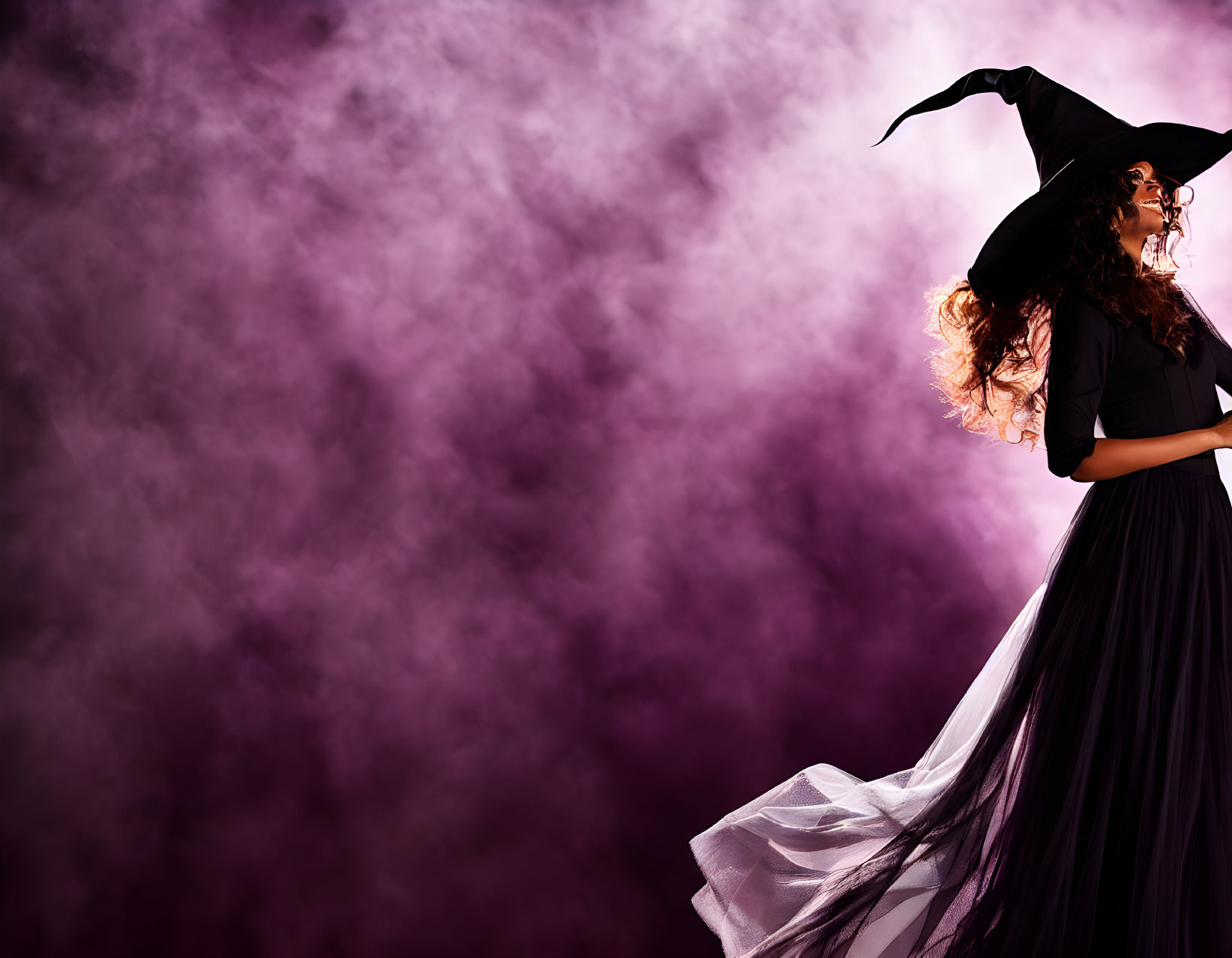 Person in witch costume with billowing cloak and pointed hat in purple smoke.