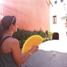 Woman with fan admiring sunlit Mediterranean village scenery