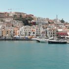 Pastel buildings, hilltop fortress, sailboat in coastal town