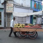 Historical street scene with horse-drawn carts, vendors, and traditional attire.