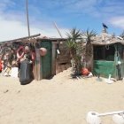 Rustic wooden huts on sandy beach with thatched roofs